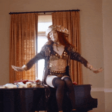 a woman is sitting on a piano with her arms outstretched in front of a window