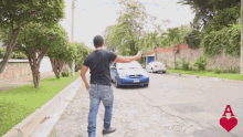 a man is standing on the side of a road with a car behind him