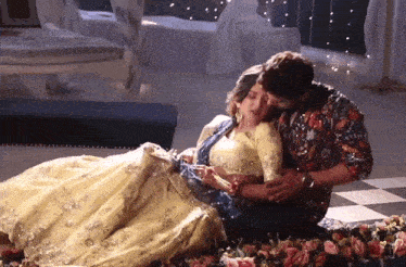 a man and a woman are laying on the floor in a room . the woman is wearing a yellow dress .