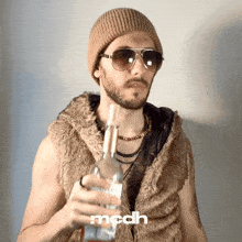 a man wearing sunglasses and a fur vest is holding a bottle and the word mcdh is on the bottom