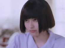 a woman with short hair and bangs is making a funny face .