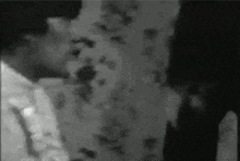 a black and white photo of a man standing next to a wall .