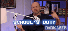 a man is sitting in front of a microphone with the words school 's out dark web behind him