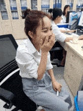 a woman sitting in a chair covering her mouth with her hands