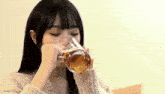 a woman is drinking a glass of beer .