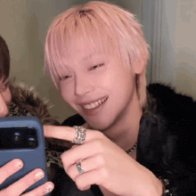 a man with pink hair is smiling while holding a phone