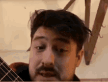 a man with a beard is looking at the camera while playing a guitar .