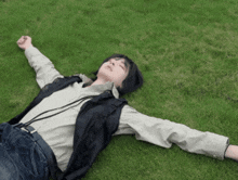 a person with their arms outstretched laying on the grass