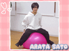 a man is sitting on a pink exercise ball with the name arata sato written below him