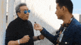 a man wearing sunglasses is being interviewed by a man wearing a name tag that says ' alvarez ' on it