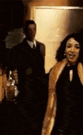 a woman in a fur coat is standing in front of a man in a suit .