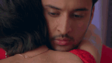 a close up of a man hugging a woman in a red dress .