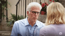 an older man wearing glasses and a tie is talking to a younger woman .