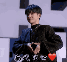 a young man is making a heart shape with his hands in front of a red heart with chinese writing on it