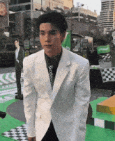a man in a white suit and tie is standing in front of a grab food truck .