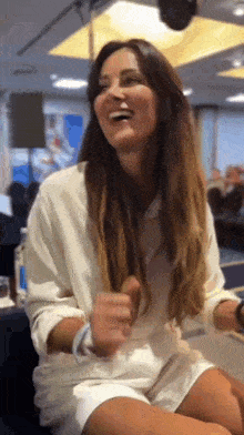 a woman in a white shirt and shorts is laughing while sitting down .