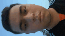 a close up of a man 's face with a blue sky behind him