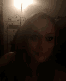 a woman is taking a selfie in the dark with a lamp in the background .