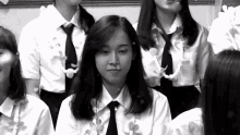 a black and white photo of a group of girls wearing white shirts and black ties