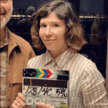 a woman is holding a clapper board with the numbers 128/140 on it