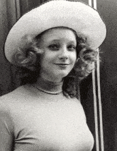 a woman with curly hair wearing a white hat and turtleneck