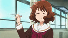 a girl in a school uniform is holding chopsticks and smiling