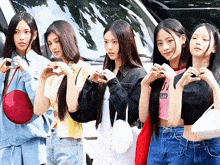a group of girls are standing next to each other making heart shapes with their hands