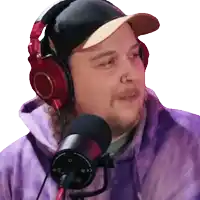a man wearing headphones and a baseball cap is talking into a microphone