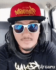 a man wearing a red hat and sunglasses is sitting in a car ..