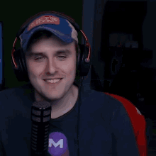 a man wearing headphones and a t-shirt with the letter m on it is laughing