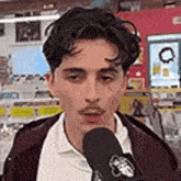 a man with a mustache is talking into a microphone .