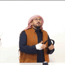 a man wearing a turban and glasses is holding a tambourine in his hands .