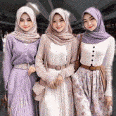 three women wearing hijabs are posing for a picture .