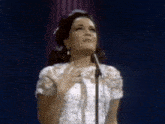 a woman in a white dress is standing in front of a microphone .