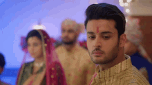 a man with a red circle on his forehead stands in front of a bride and groom