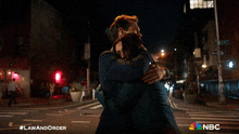 a man and a woman hugging with the nbc logo on the bottom
