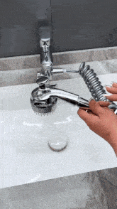 a person is holding a shower head over a bathroom sink