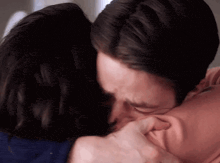 a man is kissing a woman on the cheek while they are hugging each other .