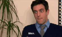 a man in a suit and tie is making a funny face and says bitch .