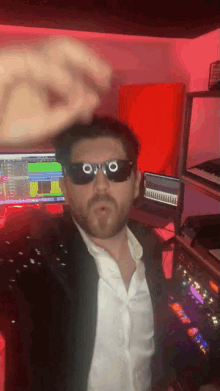 a man wearing sunglasses stands in front of a computer