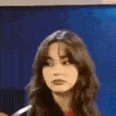 a woman with long hair is making a funny face while standing in front of a blue wall .