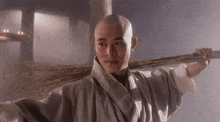 a man with a shaved head is holding a broom on his shoulder .