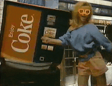 a woman is dancing in front of a coke vending machine