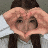 a young woman is making a heart shape with her hands