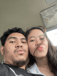a man and a woman are posing for a picture in the back of a car