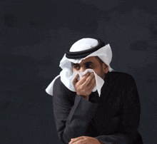 a man wearing a head scarf and covering his mouth with a napkin