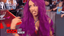 a woman with purple hair is making a funny face while standing in front of a crowd .