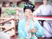a woman in a blue and white costume holds a cookie in front of her face