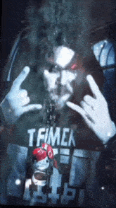 a man wearing a shirt that says tfmck is making a rock sign