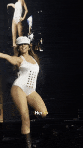 a woman in a white bodysuit is dancing on a stage with a caption that reads " her "